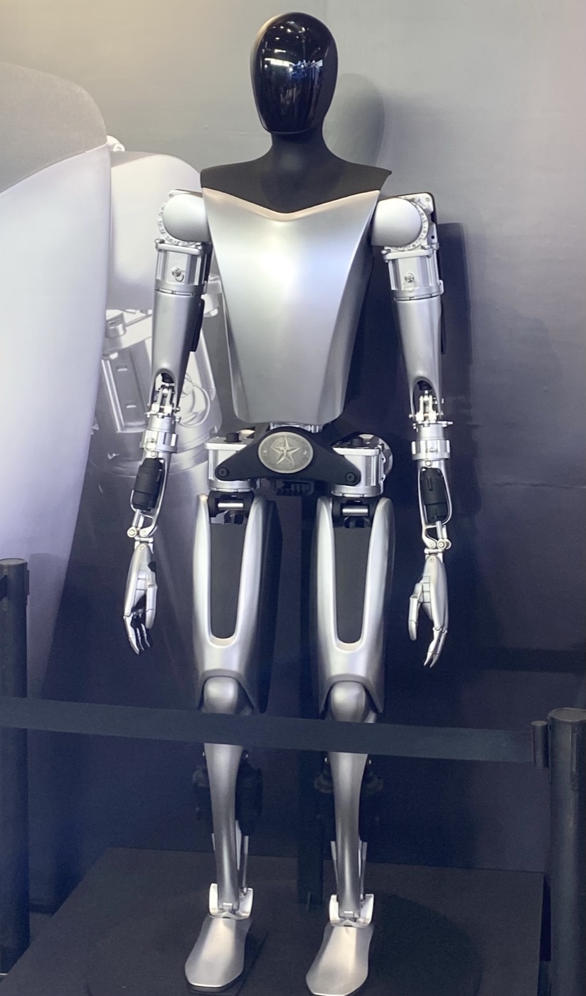 Tesla Optimus humanoid robot standing on display at an exhibition